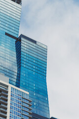 Obraz premium Tall buildings in a city with glass windows under a cloudy sky during the day
