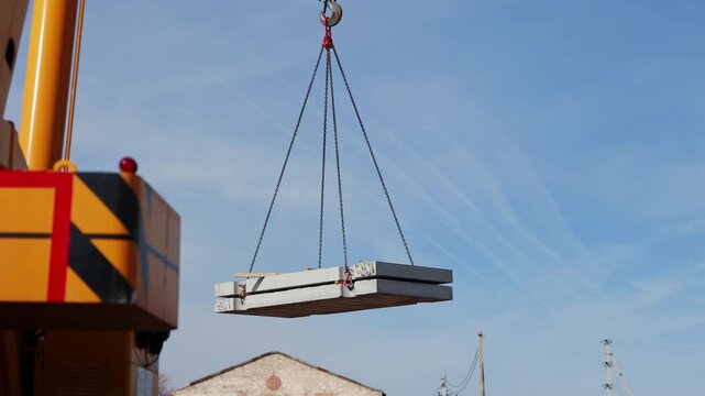 Crane lifting precast concrete slabs above construction site