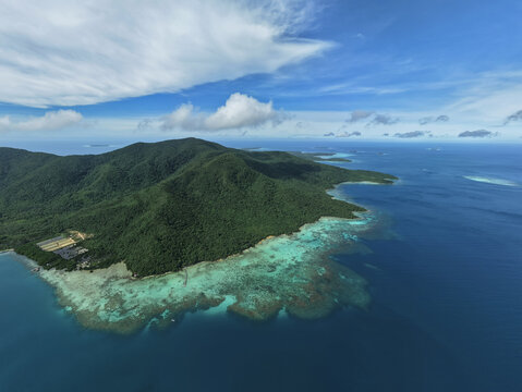 Aerial view of the island's lush greenery meeting the turquoise sea, a vibrant contrast under a vast, clear sky, Turtle Conservation, Karimunjawa, Central Java, Indonesia.
