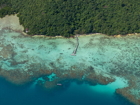 Aerial view of a pier stretching into the turquoise sea from a lush green island at Turtle Conservation, Karimunjawa, Central Java, Indonesia.