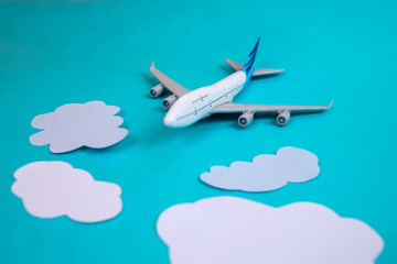 Naklejka premium Toy Airplane Soaring Through White Clouds On Blue Background