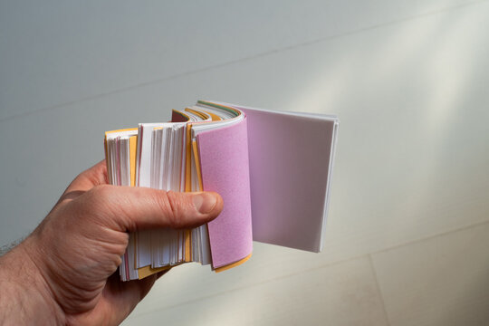 Hand Flipping Through a Stack of Colorful Paper Index Cards on a Light Background. Close-up