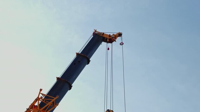 Crane hook with chain lifting upward against sky