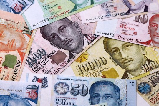 Singapore dollar money bills pile on table. Singapore banknotes of SGD currency close up.