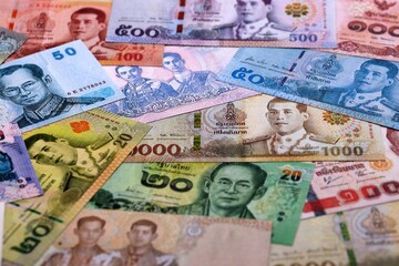 Obraz premium Thai baht money bills pile on table. Thailand banknotes of THB currency close up.