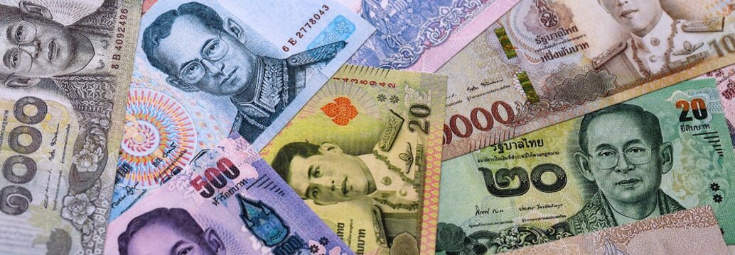 Thai baht money bills pile on table. Thailand banknotes of THB currency close up.