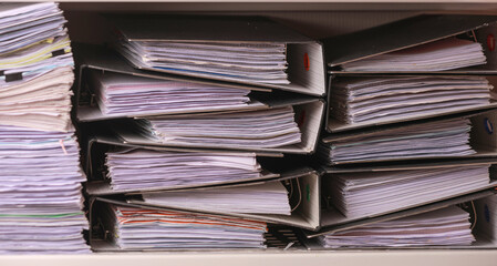 Overwhelming pile of office paper folder representing poor quality management system documentation lacking organization and creating stressful