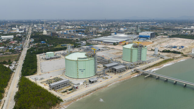 Aerial view of vast industrial facilities meet the sea, tanks gleam under the sky, a symphony of engineering and nature, Map Ta Phut, Rayong, Thailand.