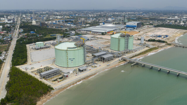 Aerial view of massive LNG tanks gleam against the backdrop of industrial structures along the coastline, Map Ta Phut, Rayong, Thailand.