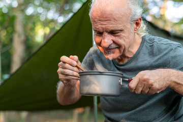 Elderly man enjoying outdoor cooking.