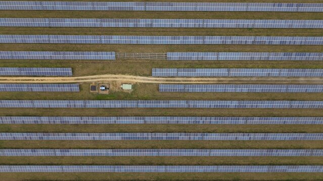 Aerial view of a vast solar farm stretches across the landscape near the former RAF Alconbury, a symphony of gray panels against the muted earth tones, Huntingdon, Cambridgeshire, United Kingdom.