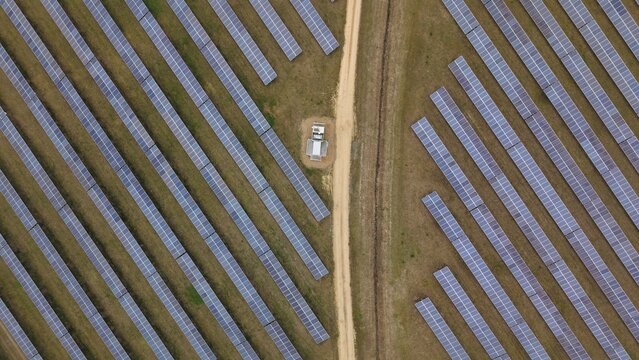 Aerial view of geometric rows of solar panels gleam under the sunlight near the former RAF Alconbury, Huntingdon, Cambridgeshire, United Kingdom.
