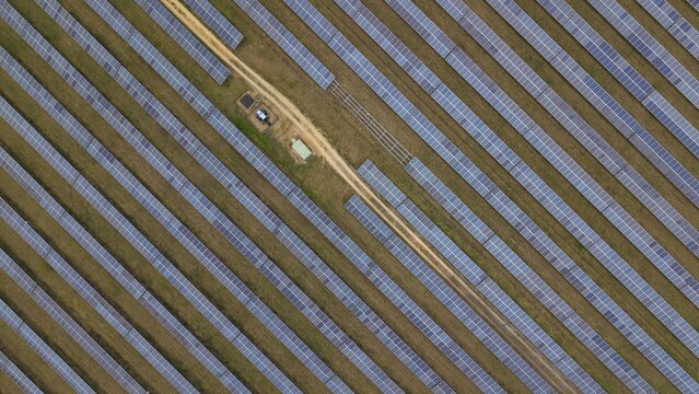 Aerial view of neat rows of solar panels stand in stark contrast to the surrounding landscape near the former RAF Alconbury, Huntingdon, Cambridgeshire, United Kingdom.
