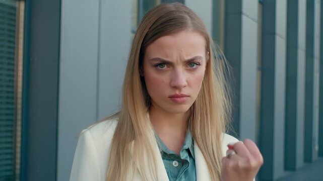 Irritated angry Caucasian business woman frowning raising clenched fist looking at camera outdoors downtown city office female businesswoman girl entrepreneur boss warning gesture aggression dominance