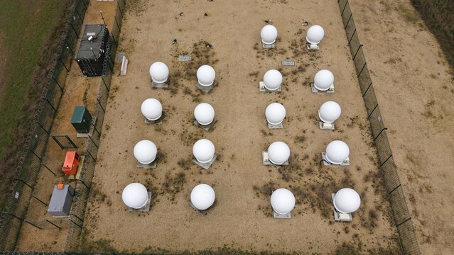 Aerial view of stark white radomes standing in geometric precision against the drab landscape, a silent sentinel, Alconbury, Huntingdon, United Kingdom.