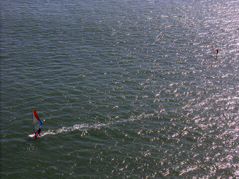 Aerial view of windsurfers dancing on the shimmering, sun-kissed waters, a symphony of motion and light, Cascais, Lisbon, Portugal.