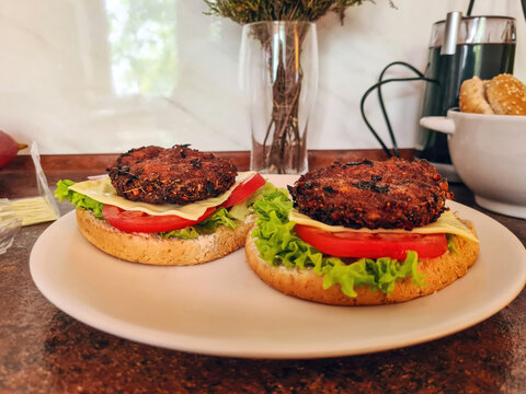 Preparing classic homemade ground beef cutlet burgers with cheese, vegetables on plate