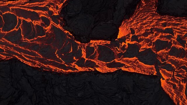 Aerial view of fiery orange lava snaking through the dark, textured volcanic rock landscape, a stark contrast of heat and cold, Grindavik, Grindavikurbaer, Iceland.