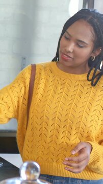Vertical video: Checking phone woman in yellow sweater tapping reader to pay at cafe touching dome