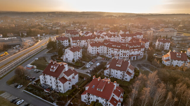 High angle aerial view of modern residential housing complex with red roofs at sunset.