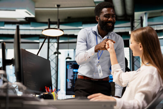 Tech company team leader doing fist bump with intern in office, satisfied with work done Happy office manager satisfied with progress of junior dev learning how to use machine learning tech