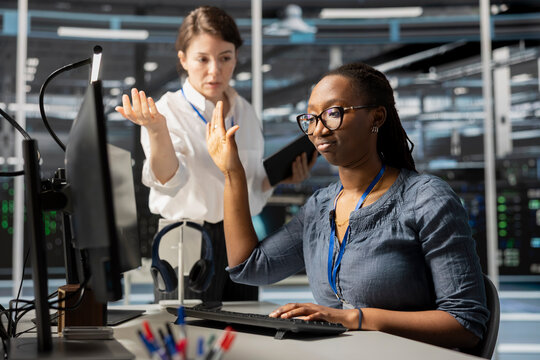 Data center engineer doing talk to the hand gesture, being dismissive of coworker berating her, reproaching performance issues. Ignorant worker in server farm ignoring verbal reprimand from colleague