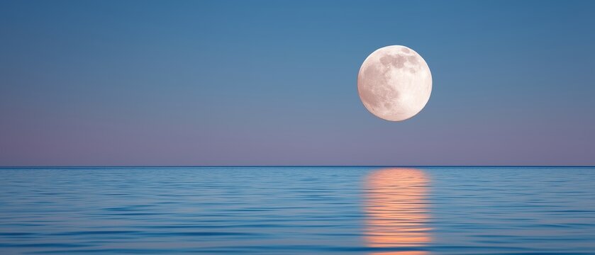 Large full moon rising over calm sea at twilight with moonlight reflection on water