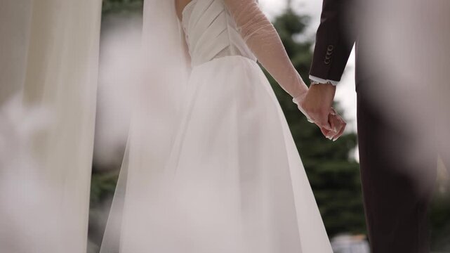 Elegant bride and groom holding hands, close-up, symbolizing love and commitment on wedding day