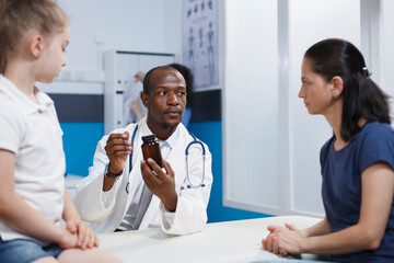 Obraz premium Caucasian mother and daughter intently listening to an African American physician describing the bottle of medicine. They discuss health care with an emphasis on thorough evaluation and treatment.