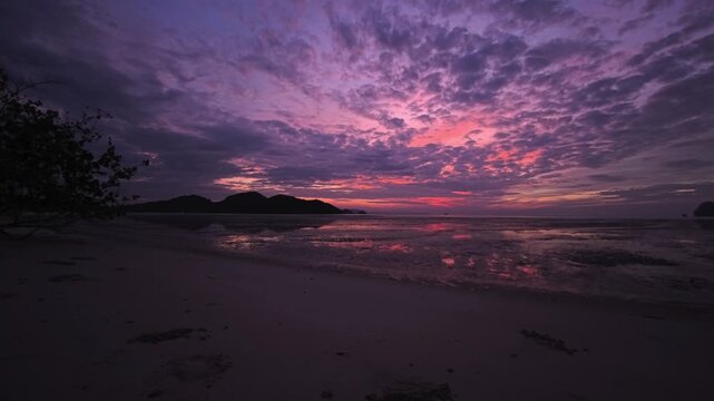 Crepuscular cloud layers reflecting on shallow shoreline in Thailand at dusk