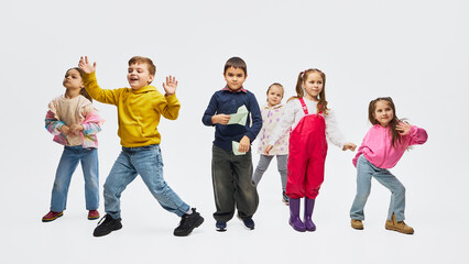Obraz premium Group of children dancing wearing colorful mid season kids fashion outfits in studio. Concept of kids fashion campaign, retail apparel promotion and playful lifestyle marketing.