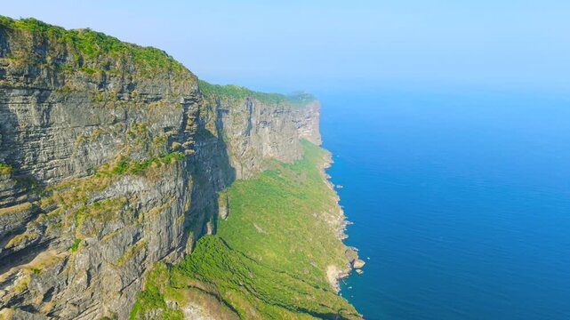 Aerial view of steep limestone cliffs and rugged coastline overlooking the Arabian Sea at Jabal Shaat on the border between Oman and Yemen.
