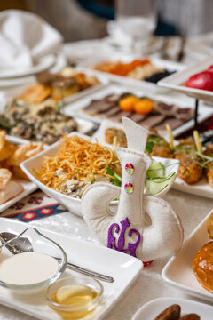 Rich Kazakh dastarkhan with baursaks, fruits, salads, sweets, national pastries, and ornate Kazakh patterns on tablecloth - authentic festive table for celebrations and cultural events.