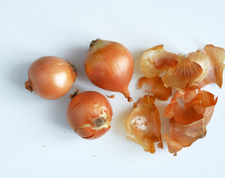 three onions, and onion skins on a white background