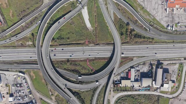 Aerial view of a complex highway cloverleaf interchange with multiple lanes and connecting ramps creating geometric patterns on the landscape, Kalochori, Thessaloniki, Greece.