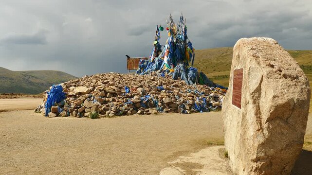 A sacred heap of stones (ovoo, obo) against the background of low hills and picturesque sky. The Mongolian landscape. Summer sunny and cloudy day.