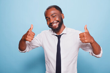 Portrait of african american man showing thumbs up sign in front of camera. Positive black individual giving like and approval, feeling happy and excited while advertising positivity. © DC Studio