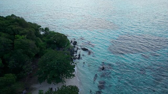 Aerial view of Tanjung Gelam Beach, where turquoise waters meet the lush green shoreline, creating a vibrant contrast of colors and textures, Karimunjawa, Central Java, Indonesia.