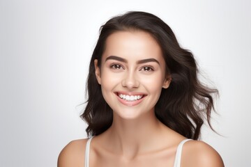 Woman smiling brightly, showcasing beauty, youth, and healthy skin against a white background