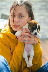Adolescent girl caring for her new pet, a small jack russell terrier puppy. Love for animals, happy...