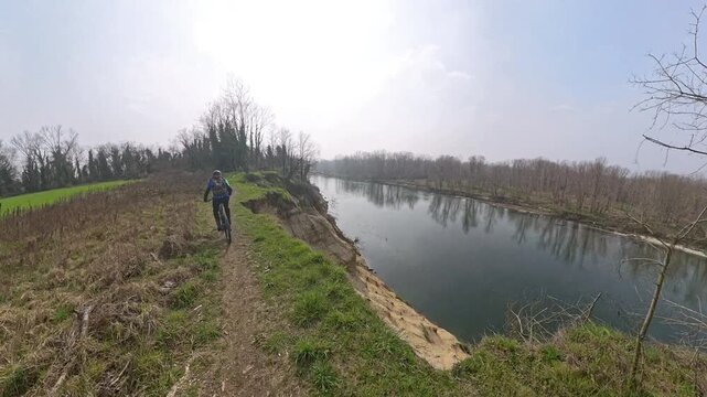 Parco del Ticino, Bereguardo, Lombardia - A bike rider pedals along a fragile sandbank near the River in the winter time