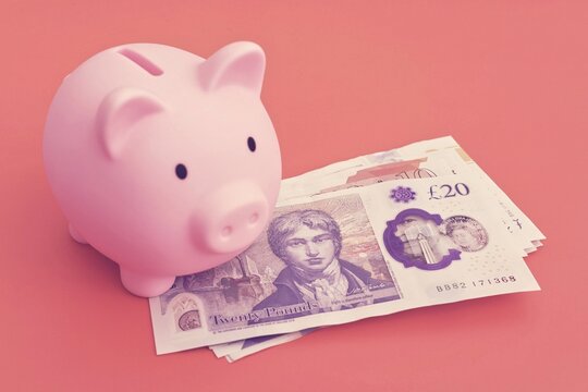  A pink piggy bank with a pound notes.