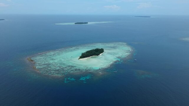 Aerial view of Cemara Kecil Island's turquoise waters and lush green vegetation, a tropical paradise surrounded by the deep blue sea, Karimunjawa, Central Java, Indonesia.