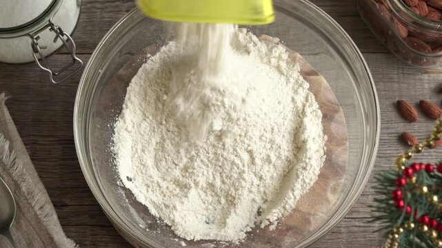 Adding flour into a glass bowl - baking homemade Christmas cookies called Kipferl or vanilla crescents