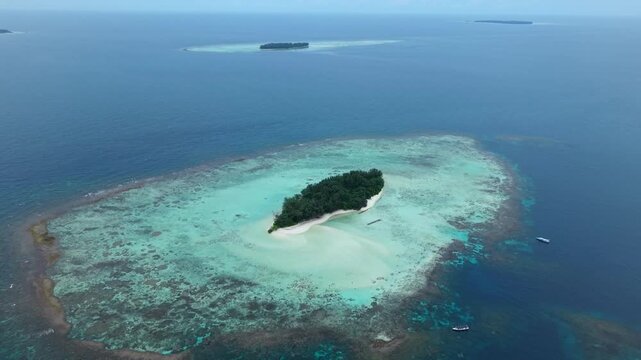 Aerial view of Cemara Kecil Island, showcasing vibrant turquoise waters and lush green vegetation contrasting with the deep blue sea, Karimunjawa, Central Java, Indonesia.