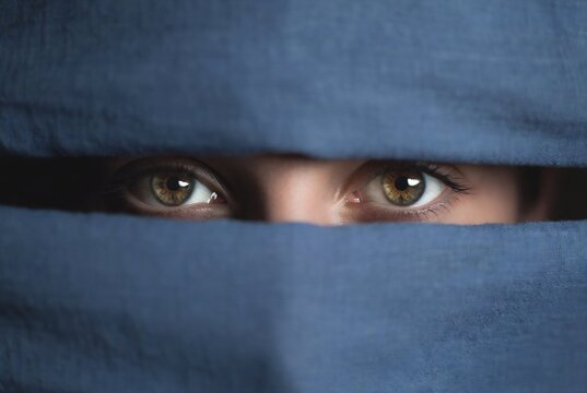 A person&rsquo;s eyes are partially hidden by a blue cloth, creating an enigmatic and slightly unsettling image.