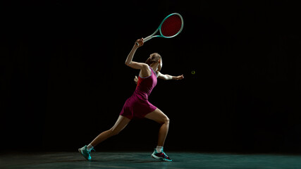 Fototapeta premium Female tennis player reaching for ball in dramatic motion. Concept of high intensity tennis training, sports advertising visuals for performance driven brand storytelling and promotion.