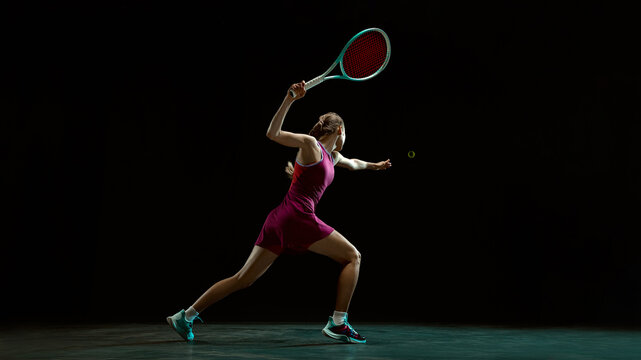 Female tennis player reaching for ball in dramatic motion. Concept of high intensity tennis training, sports advertising visuals for performance driven brand storytelling and promotion.