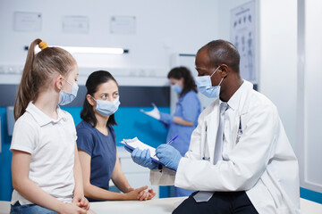 Fototapeta premium Detailed image of a doctor explaining condition and treatment to a young girl and her mother in a medical office. The atmosphere is professional, and the expertise of physician reassures the family.