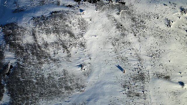 Aerial view of the stark, snow-covered landscape reveals a textured expanse with dark patches contrasting against the pristine white, Hafnarfjordur, Hafnarfjardarkaupstadur, Iceland.